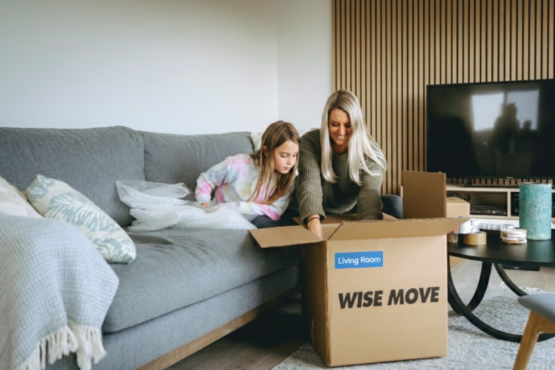 Mother and daughter placing items into packing box colour coded blue for the living/dining room